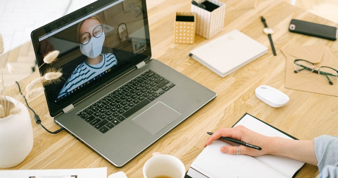 Videobellen in corona tijd vrouw met mondkapje op MacBook