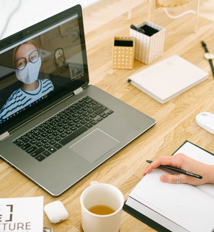 Videobellen in corona tijd vrouw met mondkapje op MacBook