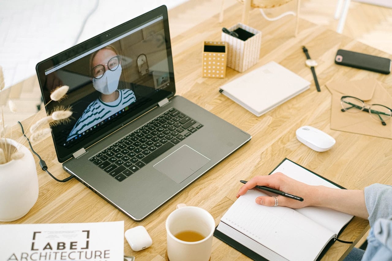 Videobellen in corona tijd vrouw met mondkapje op MacBook